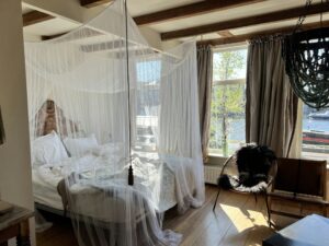 Wit muskietennet in piramidevorm gespannen over een matras in een buitensetting