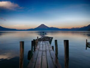 Uitzicht over Lake Atitlan met vulkanen en een houten steiger
